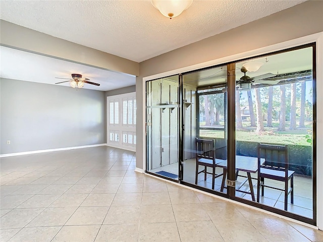 tiled empty room featuring ceiling fan, a textured ceiling, and a wealth of natural light