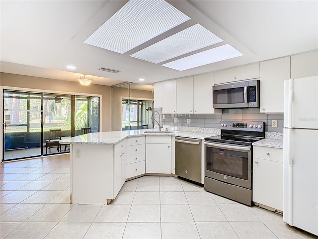 kitchen with kitchen peninsula, white cabinetry, sink, and appliances with stainless steel finishes