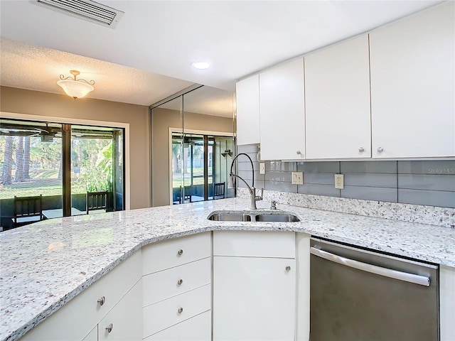 kitchen featuring backsplash, sink, stainless steel dishwasher, light stone counters, and white cabinetry