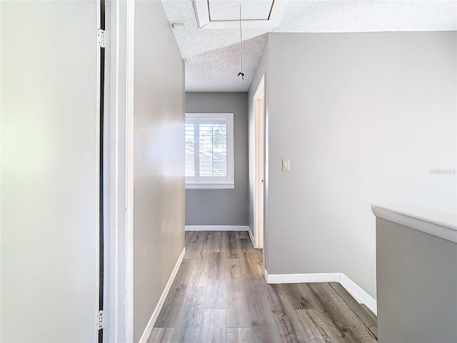 corridor featuring wood-type flooring and a textured ceiling