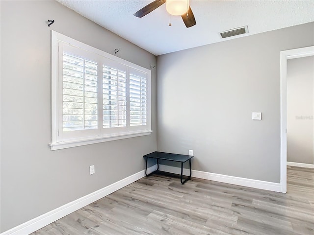 spare room with ceiling fan, light hardwood / wood-style floors, and a textured ceiling