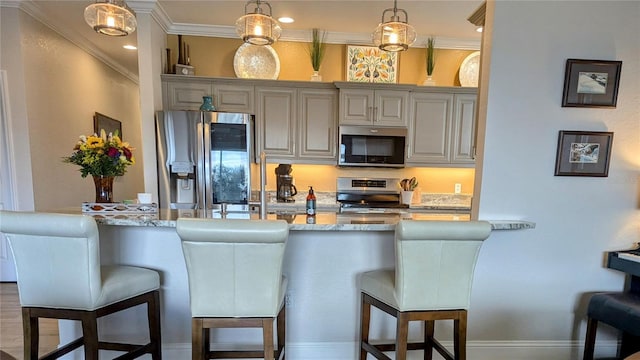 kitchen featuring stainless steel appliances, hanging light fixtures, light stone counters, and a kitchen breakfast bar