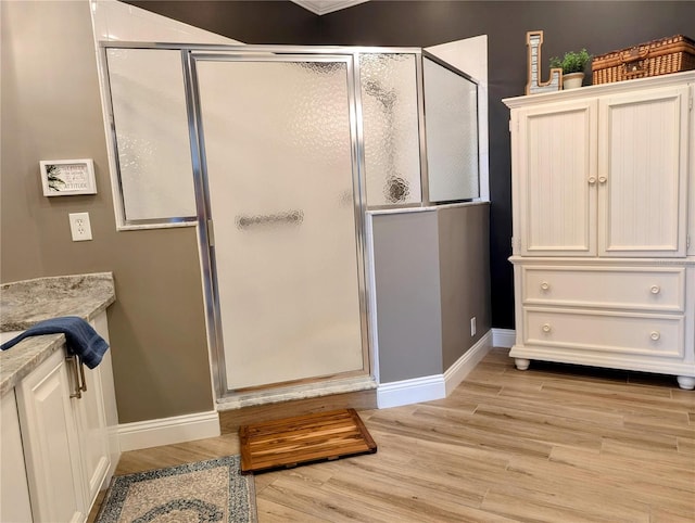 bathroom with hardwood / wood-style flooring, vanity, and an enclosed shower