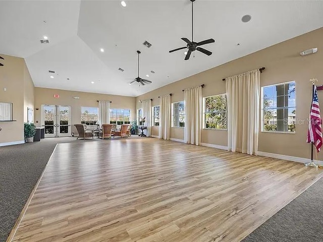 unfurnished living room with ceiling fan, high vaulted ceiling, light wood-type flooring, and french doors