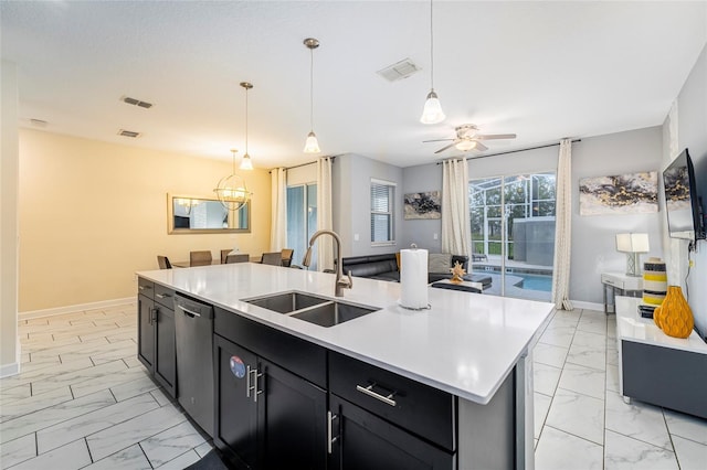 kitchen featuring stainless steel dishwasher, ceiling fan, sink, decorative light fixtures, and a center island with sink