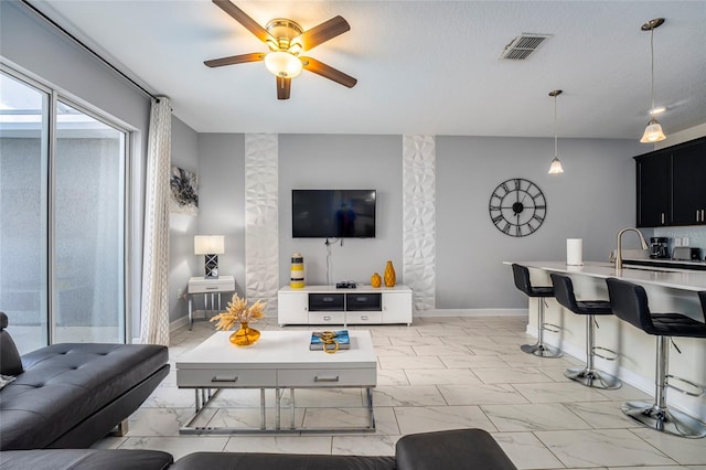 living room featuring ceiling fan, sink, and a textured ceiling