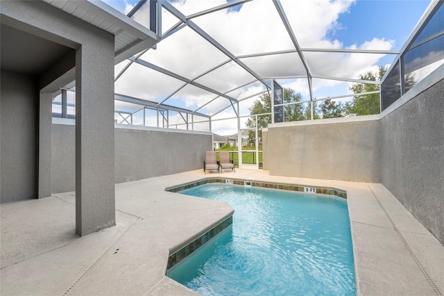 view of swimming pool with glass enclosure and a patio area