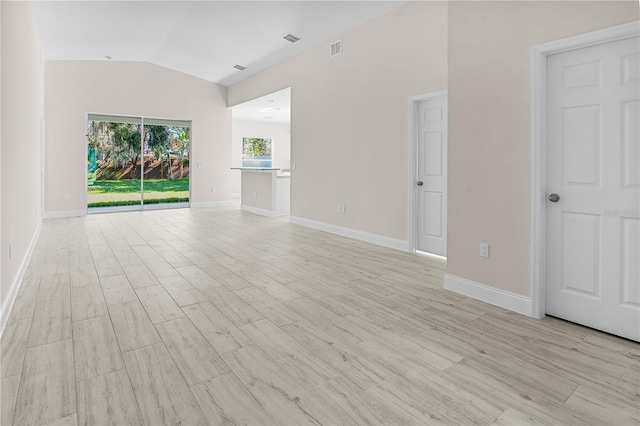 empty room featuring vaulted ceiling and light wood-type flooring