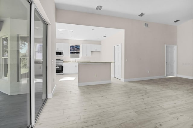 interior space featuring white cabinets, light wood-type flooring, white stove, and a kitchen island