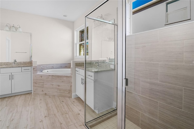 bathroom featuring plus walk in shower, wood-type flooring, and vanity