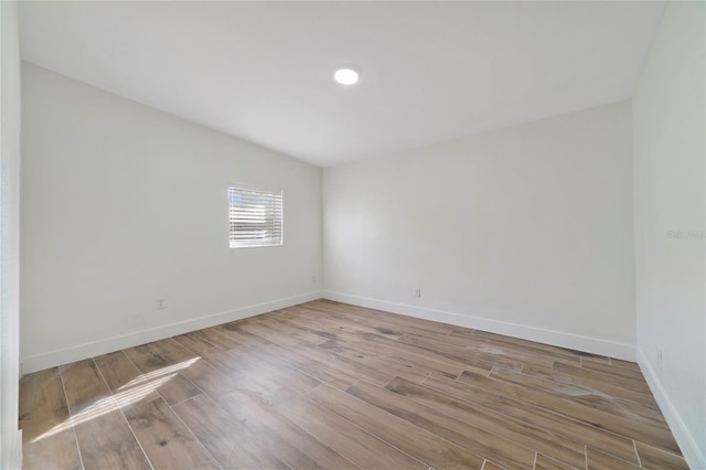 spare room with lofted ceiling and light wood-type flooring