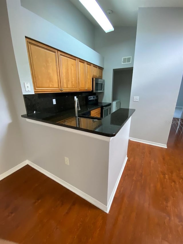 kitchen with kitchen peninsula, decorative backsplash, vaulted ceiling, and appliances with stainless steel finishes