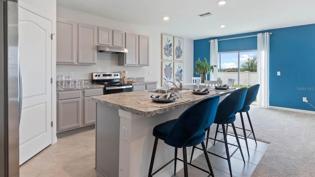 kitchen featuring gray cabinetry, stainless steel appliances, a kitchen island with sink, and light carpet