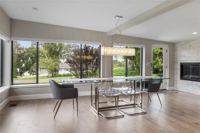 dining area with hardwood / wood-style flooring, a large fireplace, and a wealth of natural light