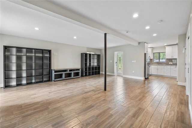 unfurnished living room featuring light wood-type flooring and sink