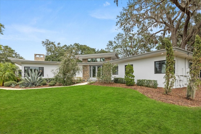 12550 Lakeshore Dr, Clermont, FL 34711 - view of front facade with a front yard, stucco siding, french doors, and a chimney
