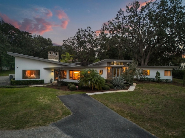 12550 Lakeshore Dr, Clermont, FL 34711 - mid-century home with a chimney, a front lawn, stucco siding, and asphalt driveway