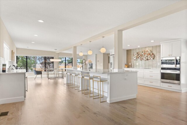 12550 Lakeshore Dr, Clermont, FL 34711 - kitchen featuring appliances with stainless steel finishes, decorative backsplash, light wood finished floors, white cabinetry, and recessed lighting