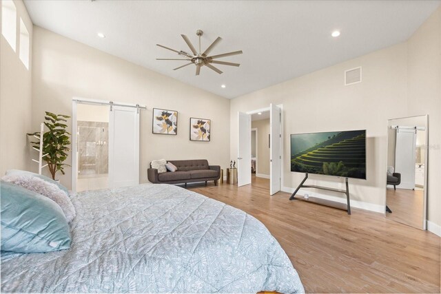 12550 Lakeshore Dr, Clermont, FL 34711 - bedroom featuring a barn door, lofted ceiling, wood finished floors, recessed lighting, and ensuite bath