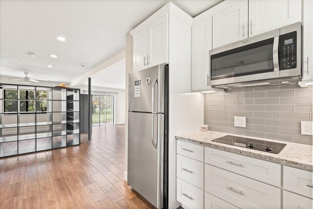 12550 Lakeshore Dr, Clermont, FL 34711 - kitchen with stainless steel appliances, light wood-style flooring, backsplash, white cabinets, and ceiling fan