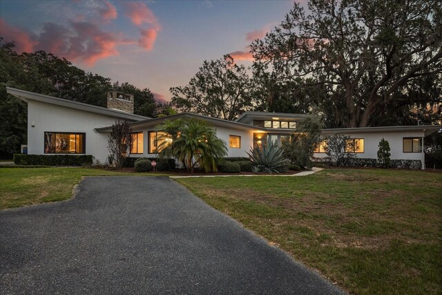 12550 Lakeshore Dr, Clermont, FL 34711 - mid-century modern home featuring stucco siding, a chimney, and a yard