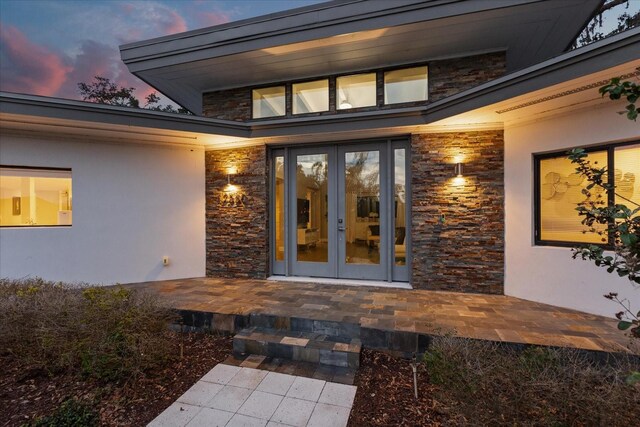 12550 Lakeshore Dr, Clermont, FL 34711 - exterior entry at dusk featuring french doors, stone siding, and stucco siding