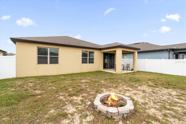 rear view of house featuring a fire pit, a yard, and a patio