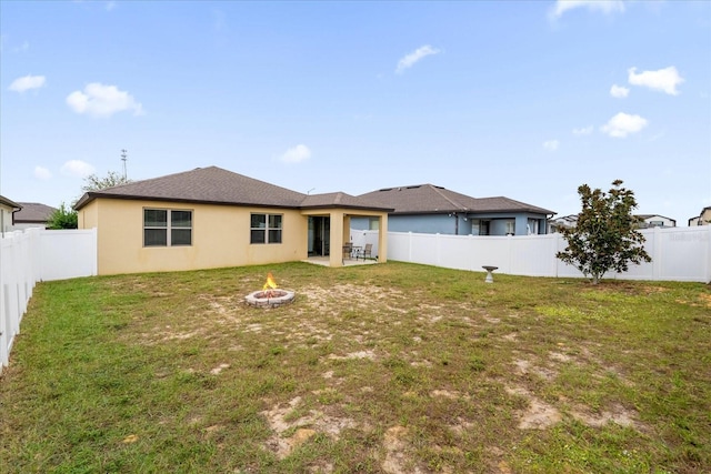 back of property with a patio area, a yard, and an outdoor fire pit