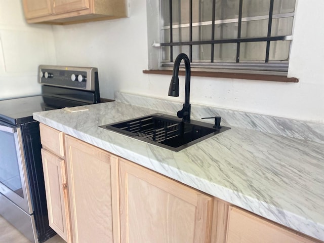 kitchen featuring light brown cabinets, stainless steel range with electric stovetop, and sink