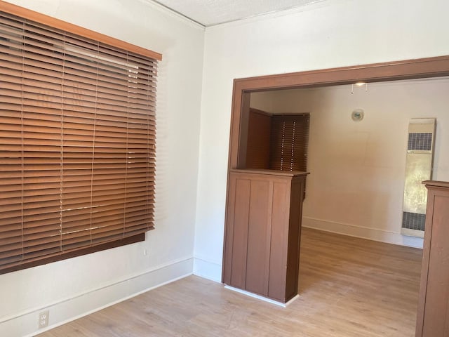 spare room with crown molding, a textured ceiling, and light hardwood / wood-style flooring