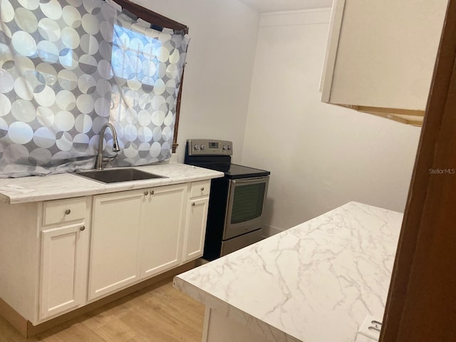 kitchen featuring light wood-type flooring, white cabinetry, stainless steel electric stove, and sink