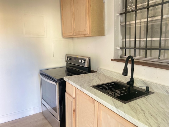 kitchen with light brown cabinets, sink, stainless steel range with electric cooktop, and light hardwood / wood-style flooring