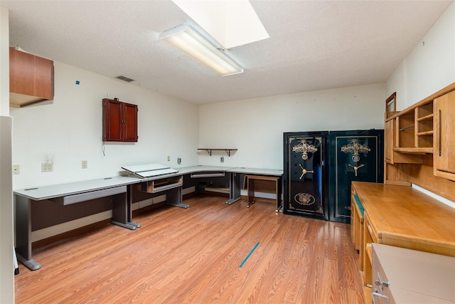 office area featuring a textured ceiling, light wood-type flooring, and a skylight