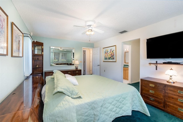 carpeted bedroom featuring a textured ceiling, ensuite bath, and ceiling fan