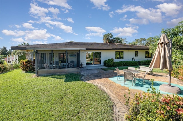 back of property with a lawn, a sunroom, and a patio