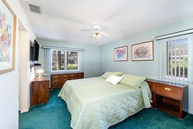 bedroom with dark colored carpet, ceiling fan, and a textured ceiling