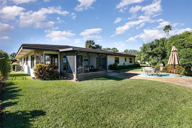 rear view of property with a sunroom, central AC unit, a patio area, and a lawn