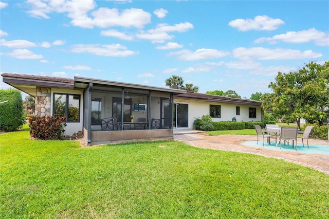 back of property featuring stone siding, a sunroom, stucco siding, a lawn, and a patio area