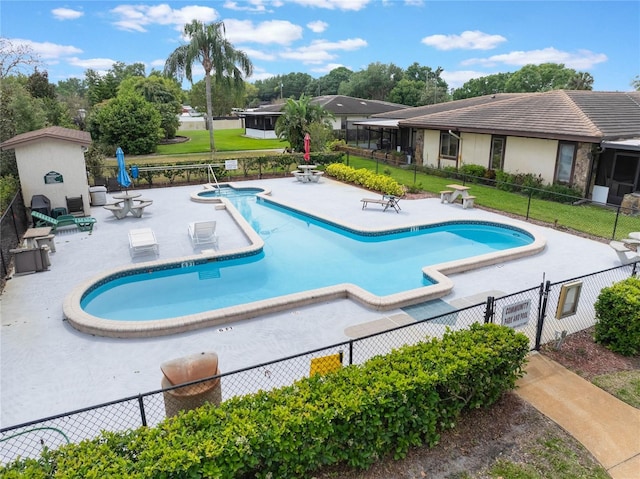 community pool with a patio, fence, and a yard