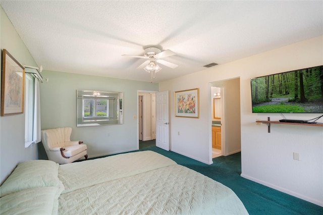 bedroom featuring a textured ceiling, visible vents, baseboards, ensuite bath, and dark colored carpet