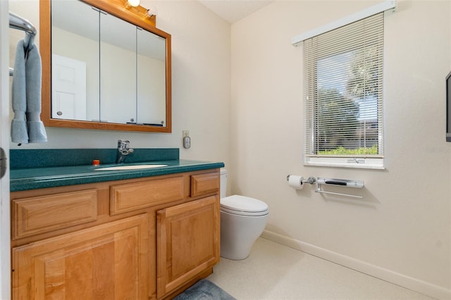 bathroom with toilet, vanity, and baseboards
