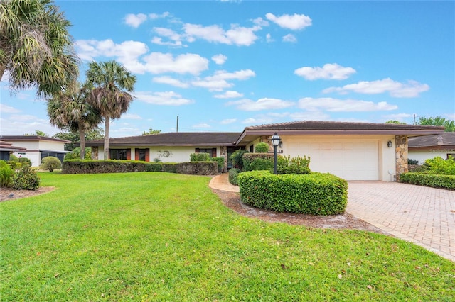 ranch-style house featuring a front yard, decorative driveway, an attached garage, and stucco siding