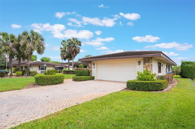 view of front of home with a front yard, decorative driveway, a garage, and stucco siding