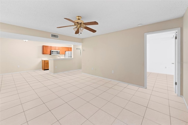 unfurnished living room with ceiling fan, light tile patterned floors, and a textured ceiling