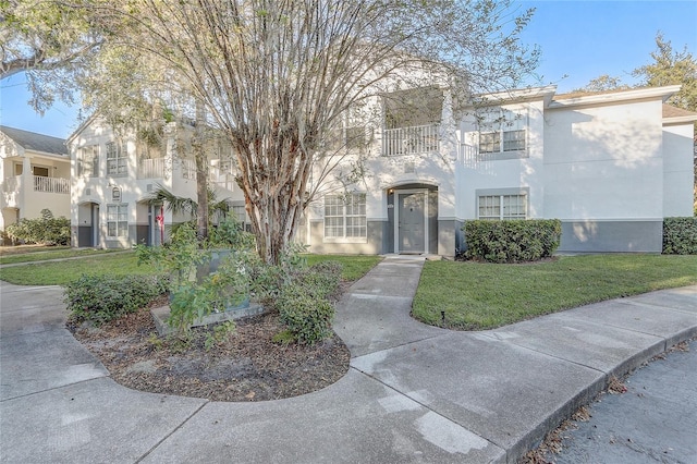 view of front facade featuring a front yard and a balcony