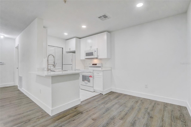 kitchen with white cabinetry, light wood-type flooring, white appliances, and kitchen peninsula