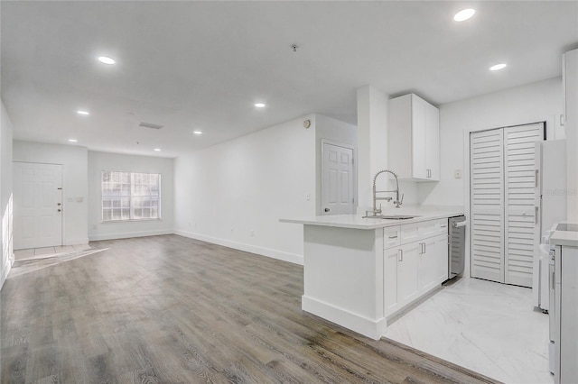 kitchen with light hardwood / wood-style floors, white cabinetry, stainless steel dishwasher, and sink