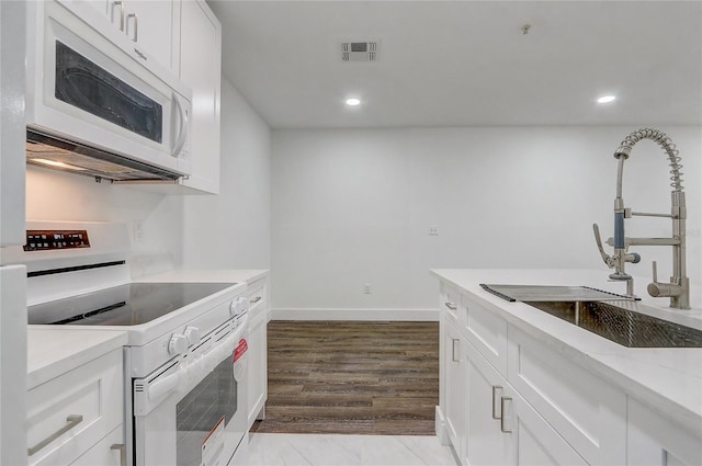 kitchen featuring light stone counters, white appliances, sink, white cabinets, and light hardwood / wood-style floors