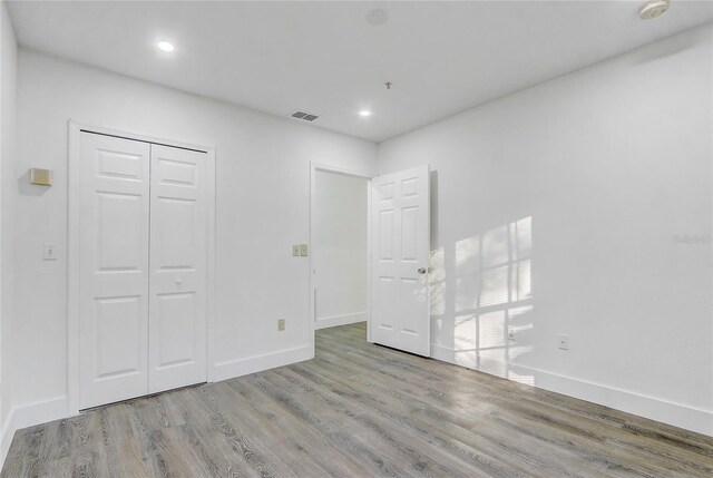 unfurnished bedroom with a closet and light hardwood / wood-style flooring