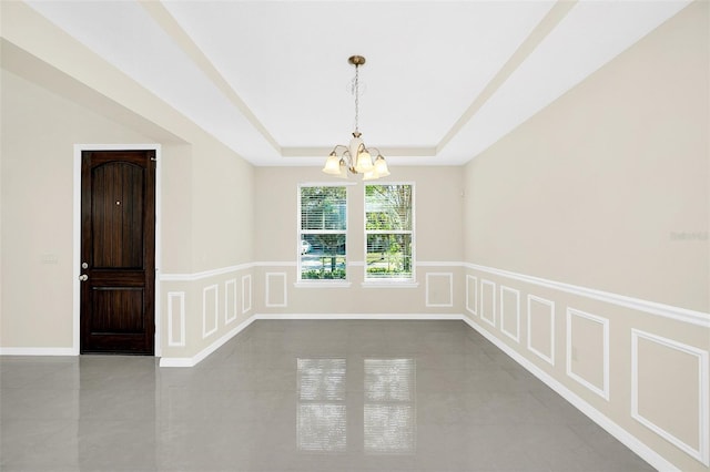 unfurnished room featuring concrete floors, a tray ceiling, and a notable chandelier